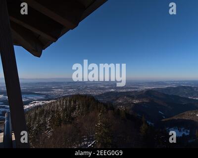 Atemberaubende Luftaufnahme über Schwarzwaldhügel, Rheintal, Stadt Freiburg und Vogesen am Horizont mit schneebedeckter Landschaft im Winter. Stockfoto