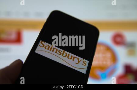 Viersen, Deutschland - Februar 9. 2021: Nahaufnahme des Smartphone-Bildschirms mit Logo-Schriftzug von sainsbury Supermarkt, verschwommener Website-Hintergrund Stockfoto