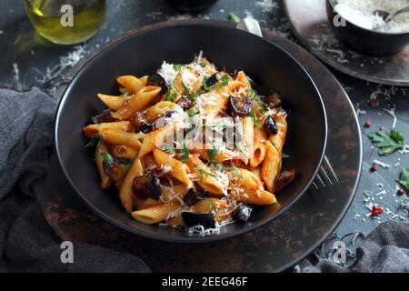 Pasta alla norma: Italienische Pasta mit Auberginen, Tomaten und Parmesankäse auf dunklem Tisch. Draufsicht. Stockfoto