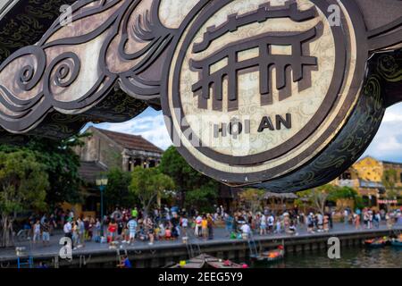 Hoi an, Vietnam - 27 Jul 2019: Historische Stadt am Flussufer mit gelben Gebäuden und Touristen. Hoi ein Stadtname Banner auf Brücke. Vietnamesischer Tourist att Stockfoto