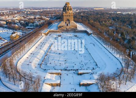 Leipzig, Deutschland. Februar 2021, 13th. Leipzigers Schlittschuh über das Eis auf dem See der tausend Tränen vor dem Denkmal zur Schlacht der Nationen. Nach frostfreien Tagen laden zumindest die flachen Teiche zum Schlittschuhlaufen ein. (Luftaufnahme mit Drohne) Quelle: Jan Woitas/dpa-Zentralbild/ZB/dpa/Alamy Live News Stockfoto