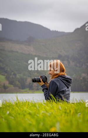 Mädchen im Gras am See sitzend, Sete Cidades, Sao Miguel Insel, Azoren, fotografieren. Stockfoto