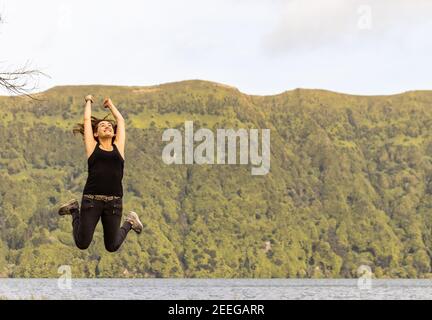 Frau glücklich Springen in der Luft, im Urlaub, Gefühl frei, Sete Cidades See, Azoren. Stockfoto