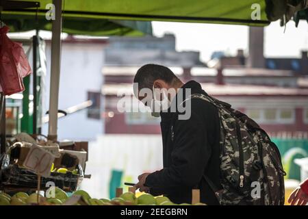 BELGRAD, SERBIEN - 10. OKTOBER 2020: Mann mittleren Alters kauft Lebensmittel mit seinem Smartphone in einem Belgrader grünen Bauernmarkt in Gesichtsmaske Stockfoto