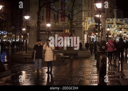 BELGRAD, SERBIEN - 27. DEZEMBER 2020 zwei junge Frauen, Freunde, reden Bilder und schießen mit ihrem Smartphone Handy auf kneza mihalova stre Stockfoto