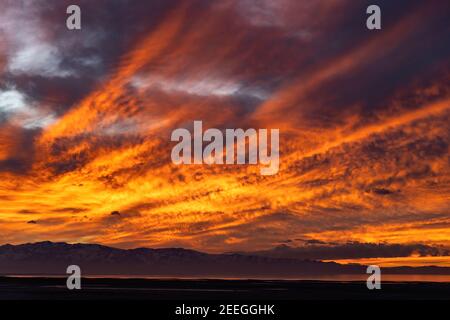 Das feurige Licht der untergehenden Sonne reflektiert auf dem Great Salt Lake, während es über den Stansbury Bergen in Tooele County, Utah, USA untergeht. Stockfoto