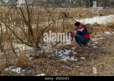 Fotograf am Ufer, Schleichen Löcher in der Morgenlicht in der Winterkälte. Ufer des Bodensees mit Schilf, Büschen und Bäumen. Schleienlöcher, Hart Stockfoto