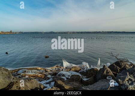 Schleichenlöcher im Morgenlicht in Winterkälte. Ufer des Bodensees mit natürlichem Eis schuf Skulpturen. deutsches Ufer mit Lindau im Hintergrund Stockfoto