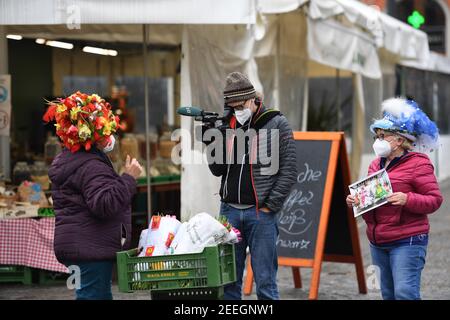 München, Deutschland. Februar 2021, 16th. Marktfrauen stehen am Faschingsdienstag mit Obstkisten am Viktualienmarkt und werden von einem Kameramann des Bayerischen Rundfunks gefilmt. Der traditionelle Tanz der Marktfrauen findet in diesem Jahr aufgrund der Corona-Pandemie nicht statt. Quelle: Felix Hörhager/dpa/Alamy Live News Stockfoto