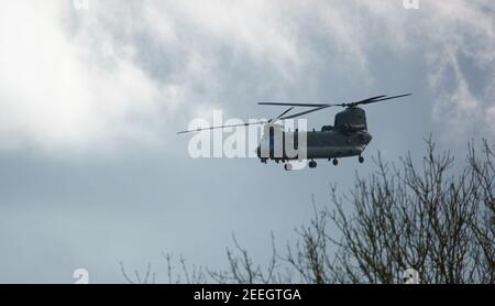 RAF Chinook Tandem-Rotor CH-47 Hubschrauber fliegt schnell und tief in einem wolkigen blauen grauen Himmel auf einer militärischen Kampfübung, Wilts UK Stockfoto