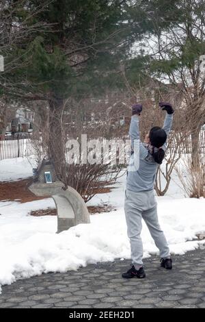 An einem kalten Wintermorgen tanzt und trainiert eine chinesisch-amerikanische Frau Musik von ihrem iphone. In Flushing, Queens, New York City. Stockfoto