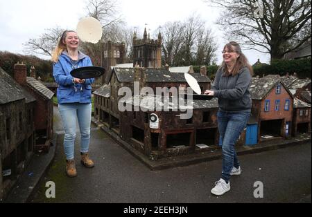 Mutter und Tochter Freiwillige Niki (rechts) und Rachel üben ihre Pfannkuchen werfen in den Straßen von Wimborne Modellstadt und Gärten, während sie am Wimborne Minster virtuellen Pfannkuchen Rennen teilnehmen. Bilddatum: Dienstag, 16. Februar 2021. Stockfoto