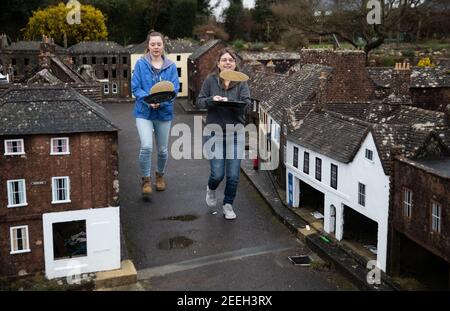 Mutter und Tochter Freiwillige Niki (rechts) und Rachel üben ihre Pfannkuchen werfen in den Straßen von Wimborne Modellstadt und Gärten, während sie am Wimborne Minster virtuellen Pfannkuchen Rennen teilnehmen. Bilddatum: Dienstag, 16. Februar 2021. Stockfoto