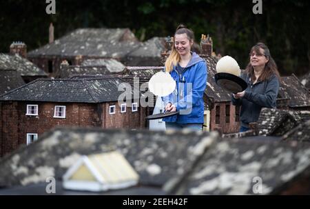 Mutter und Tochter Freiwillige Niki (rechts) und Rachel üben ihre Pfannkuchen werfen in den Straßen von Wimborne Modellstadt und Gärten, während sie am Wimborne Minster virtuellen Pfannkuchen Rennen teilnehmen. Bilddatum: Dienstag, 16. Februar 2021. Stockfoto