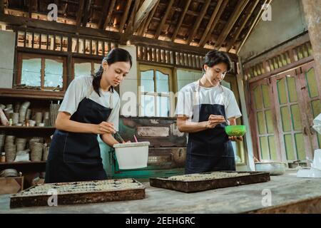 Ein Paar Kuchenmacher tragen Schürzen kneten die Teig in einer Schüssel, während Sie einen Kuchen in der backen Küche Stockfoto