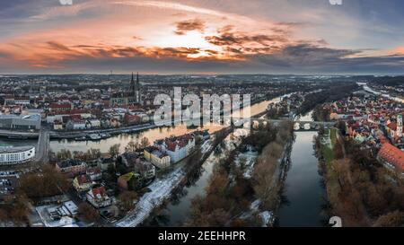 Panorama der Stadt Regensburg in Bayern mit der Donau der Dom und die Steinbrücke im Winter mit Schnee und Eis bei Sonnenuntergang, Deutschland Stockfoto