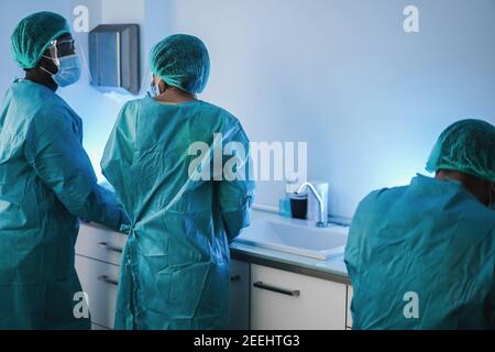 Multirassische medizinische Arbeiter in Gefahrgutanzug arbeiten im Laborkrankenhaus Während Coronavirus Ausbruch - Fokus auf Mitte Frau Stockfoto