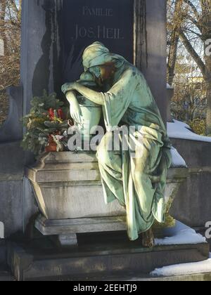 Mülheim AN DER RUHR, DEUTSCHLAND - 13. Feb 2021: Ein Grab auf dem alten Friedhof von Mülheim, mit einem schönen weinenden Engel. Alles mit Schnee bedeckt. Blau sk Stockfoto