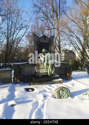 Mülheim AN DER RUHR, DEUTSCHLAND - 13. Feb 2021: Ein Grab auf dem alten Friedhof von Mülheim, mit einem schönen weinenden Engel. Alles mit Schnee bedeckt. Blau sk Stockfoto