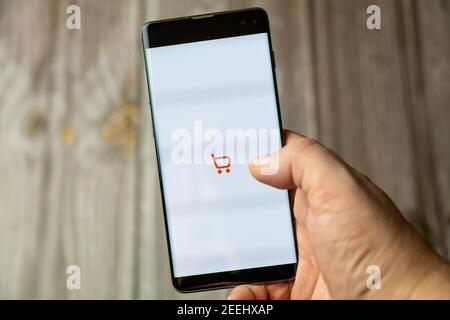 Ein Mobiltelefon oder Mobiltelefon, das in einem gehalten wird Hand mit der sainsbury's Shopping-App auf dem Bildschirm geöffnet Stockfoto