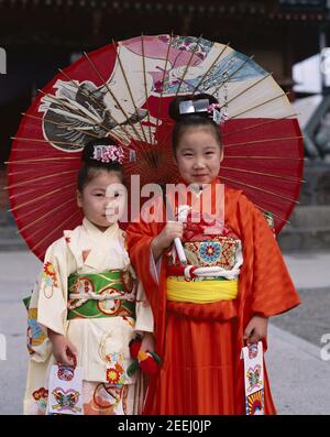 Japan, Honshu, Tokio, zwei Mädchen gekleidet in traditionellen Kimono Holding Papier Sonnenschirme für den jährlichen 7-5-3 (Shichi-go-san) auf November 15. Stockfoto