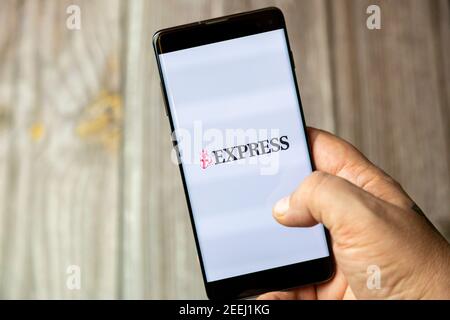 Ein Mobiltelefon oder Mobiltelefon, das in einem gehalten wird Hand mit der Express News App geöffnet auf dem Bildschirm Stockfoto