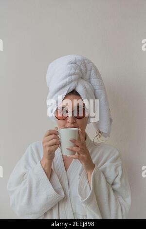 Eine Frau mit Gläsern im Bademantel und einem Handtuch Im Hotel trinkt man Kaffee Stockfoto