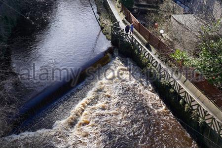 Edinburgh, Schottland, Großbritannien. Februar 2021, 16th. Schneeschmelze auf einem schnell fließenden Wasser von Leith mit vielen Wehren und Wasserfällen überströmend mit turbulentem Weißwasser und der Gehweg unpassierbar an Orten, die einen Umweg erfordern. VogelVogelperspektive auf einen schnell fließenden Wasserfall. Kredit: Craig Brown/Alamy Live Nachrichten Stockfoto