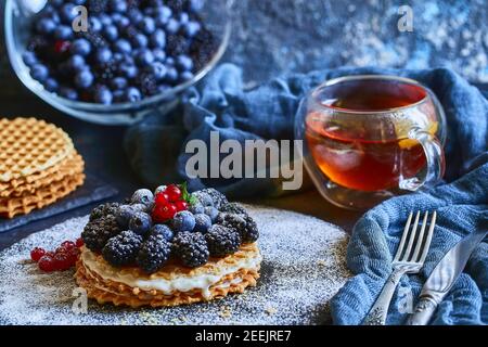 Selbstgemachte Waffeln mit Heidelbeeren und Brombeeren, Puderzucker auf einer Steinplatte mit Obst. Geringe Tiefenschärfe. Stockfoto
