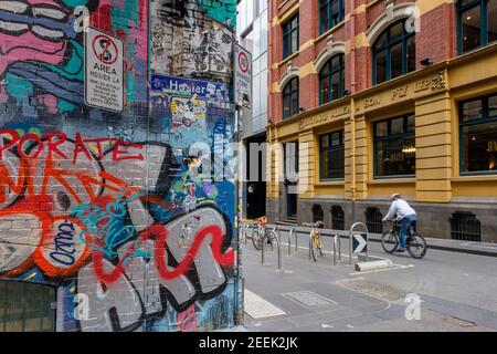 Eine Person radelt an Graffiti-Kunstwerken in der Hosier Street in Melbourne, Australien vorbei Stockfoto