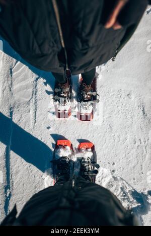 Vertikale Draufsicht auf zwei Schneeschuhfüße im Schnee Stockfoto