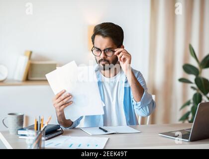 Betroffener Arabischer Geschäftsmann In Brillen, Der Finanzdokumente Am Arbeitsplatz Liest Im Büro Stockfoto