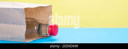 Alkoholflasche mit rotem Kork in Papiertüte auf gelbem und blauem Hintergrund. Stockfoto