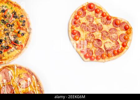 Drei verschiedene Arten von Pizzen, rund und Herz auf weißem Hintergrund mit Kopierraum, Salami, Pilze, Tomaton, Pepperoni, Kirschtomate und Stockfoto