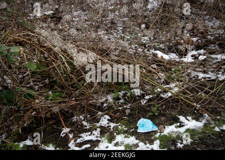 London, Hackney Marshes. Ausrangierte Gesichtsmask im Schnee Stockfoto