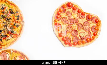 Drei verschiedene Arten von Pizzen, rund und Herz auf weißem Hintergrund mit Kopierraum, Salami, Pilze, Tomaton, Pepperoni, Kirschtomate und Stockfoto