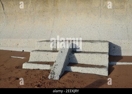 Stufen zu Nirgendwo unter einer geschwungenen Ufermauer. Stockfoto