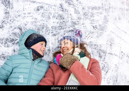 Mutter und Sohn liegen auf gefrorener Seenoberfläche und Lächelnd Stockfoto