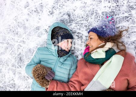 Mutter und Sohn liegen auf gefrorener Seenoberfläche und Lächelnd Stockfoto