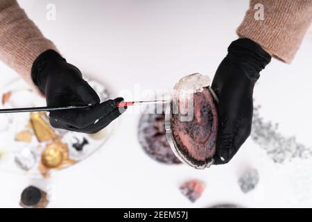 Künstlerische Untersetzer. Eine junge Frau schafft Untersetzer aus Harz. Geschenkverpackung.Design-Element für ein Geschenk. Erstellung. Blick von oben. Künstlerischer Hintergrund. Stockfoto