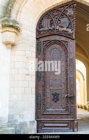 Hellbraune, antike Holztüren mit Schnitzereien und Mustern. Metallgriffe aus Gold. Ein halbkreisförmiges Gewölbe. Eingang zum Haus. Stockfoto