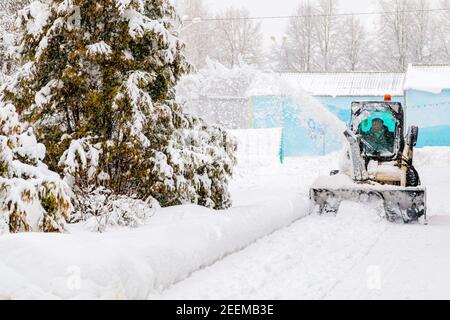 Im Winter räumt der Traktor die schneebedeckte Straße werfen Schnee in Richtung Weihnachtsbaum Stockfoto