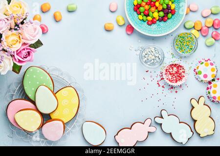 Ostern Backen Hintergrund. Ostern bunten Lebkuchen, Süßigkeiten und Süßwaren Topping Dressing auf blauem Hintergrund. Festliches Hintergrundkonzept Stockfoto