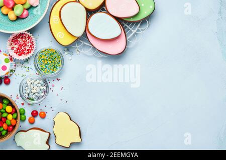 Ostern Backen Hintergrund. Ostern bunten Lebkuchen, Süßigkeiten und Süßwaren Topping Dressing auf blauem Hintergrund. Festliches Hintergrundkonzept Stockfoto