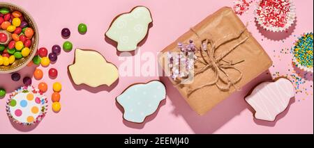 Ostern Backen Hintergrund. Ostern bunten Lebkuchen, Süßigkeiten, verstreute Süßwaren Topping Dressing und Geschenkbox auf rosa Hintergrund. Celebrator Stockfoto