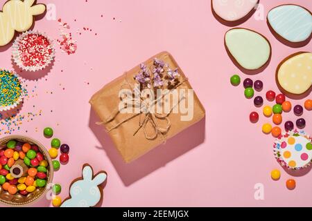 Ostern Backen Hintergrund. Ostern bunten Lebkuchen, Süßigkeiten, verstreute Süßwaren Topping Dressing und Geschenkbox auf rosa Hintergrund. Celebrator Stockfoto