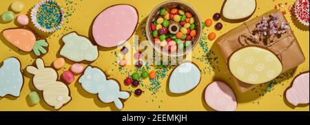 Ostern Backen Hintergrund. Ostern bunten Lebkuchen, Süßigkeiten, verstreute Süßwaren Topping Dressing und Geschenkbox auf gelbem Hintergrund. Feiern Stockfoto