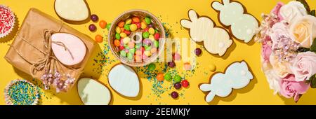 Ostern Backen Hintergrund. Ostern bunten Lebkuchen, Süßigkeiten, verstreute Süßwaren Topping Dressing und Geschenkbox auf gelbem Hintergrund. Feiern Stockfoto