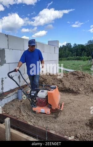 Bauarbeiten auf der Baustelle, Bodenverdichtung mit einer vibrierenden Platte, manuelle Ausrüstung.neu Stockfoto