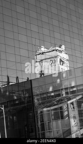 Senkrechte Graustufenaufnahme der Gebäudespiegelung auf dem Glas Gebäude in Bukarest Stockfoto